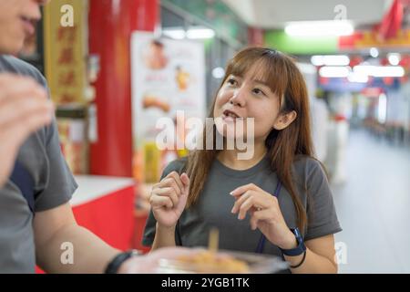 Chinesisches malaysisches Paar in den 30ern kaufte und aß Kinako Mochi Dessert im Shop im chinesischen Tempel in Kuala Lumpur, Malaysia. Stockfoto