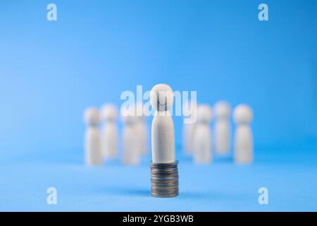 Holzfiguren stehen auf Geldmünzen aus der Menge. Erfolg oder Talent, und denken Sie an ein anderes kreatives Konzept. Finanzinvestitionen und Ruhestand Stockfoto