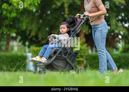 Mutter schiebt Kleinkind Kinderwagen und geht im Park Stockfoto