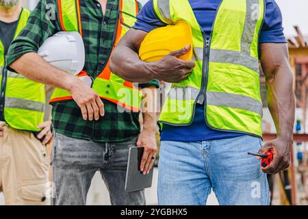 Nahaufnahme-Arbeiter Teamarbeit Servicemitarbeiter in der Bauindustrie. Verschiedene Mitarbeiter stehen zusammen. Konzept des Personals für Industrieingenieure. Stockfoto