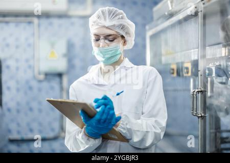 Hygienearbeiterinnen arbeiten im Wissenschaftslabor. Leute in der pharmazeutischen Medizin Produktionsmaschine Inspektor. Stockfoto