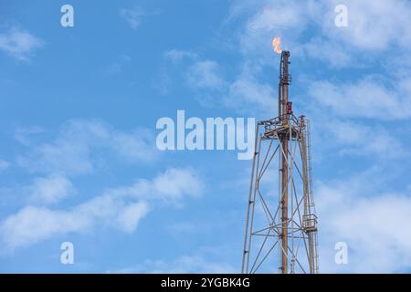 Methangas-Feuer-Plattform mit hohem Flare-Stack-Fackelturm in Raffinerien-Erdölanlagen oder Flammenbrand bei Offshore-Ölgewinnung. Stockfoto