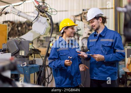 Zufriedene Techniker-Team-Service ersetzen defekte Teile des automatischen Roboterschweißarms der Industrie. Mechanikerteam Reparatur Wartung Robotermaschine in Arbeitsauftrag Stockfoto