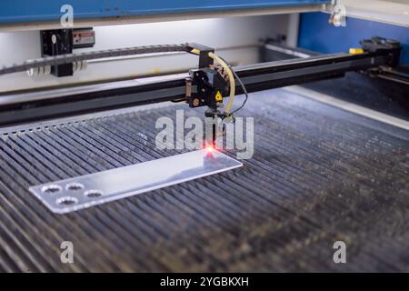 Industrielle CO2-Laserschneidemaschine mit hohem Leistungsdruck, die mit rotem Laserstrahl auf Acryl- oder Glasplatte arbeitet Stockfoto