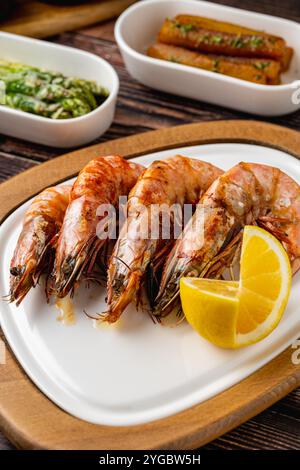 Rote Garnelen oder Tigergarnelen auf einem weißen Teller mit Gemüse und Tomaten. Tigergarnelen Stockfoto