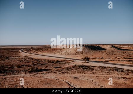 Blick vom Aussichtspunkt auf den Northwest Coastal Highway. Lange Strecke der Kurvenstraße in Westaustralien. Schmutz, Büsche und Felsen umgeben. Stockfoto