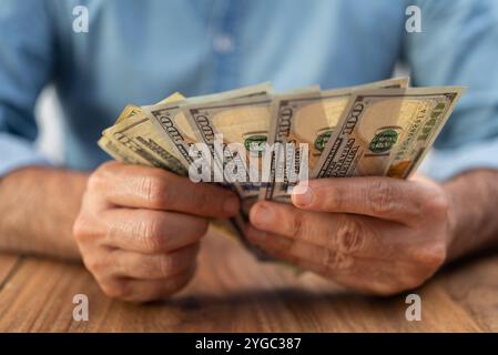 Der Buchhalter der man-Firma hält Dollar-Banknoten, wobei die für die Zahlung von Dienstleistungen erforderliche Menge zählt Stockfoto