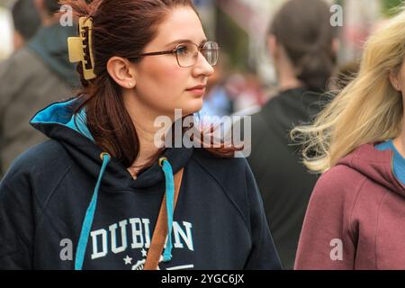 Straßenporträt von Dublins Frau. Eine blonde junge Frau in einer schwarzen Jacke geht in der Dublin Street. Dublin, Irland. Stockfoto