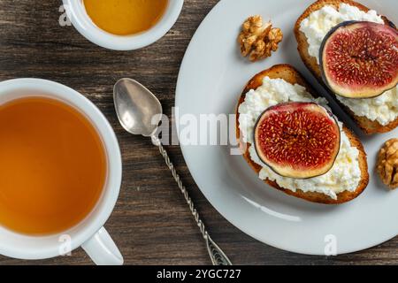 Zwei Sandwiches mit frischen Feigenscheiben, weißem Hüttenkäse, Honig und Walnüssen auf Toastbrot auf einem weißen Teller, Blick von oben, Nahaufnahme. Gesunde Ernährung. Entf Stockfoto