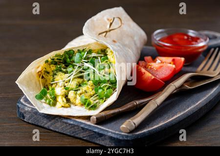 Hausgemachte Burrito-Wraps mit Rührei-Omelett und Mikrogrün für gesundes Frühstück auf Holzbrett, Nahaufnahme Stockfoto
