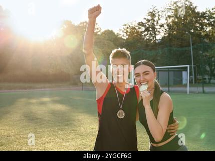 Porträt glücklicher Gewinner mit Medaillen im Stadion am sonnigen Tag. Leerzeichen für Text Stockfoto