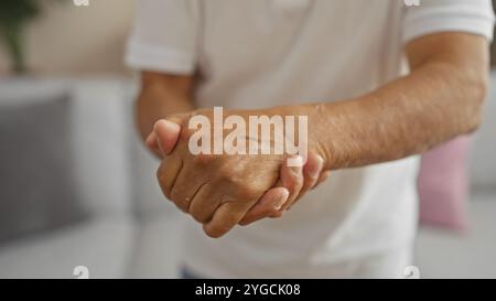 Ein Mann mittleren Alters, der seine Hände in einem Raum hält, schlägt eine Inneneinrichtung mit reifem Fokus in einer ruhigen Umgebung vor. Stockfoto