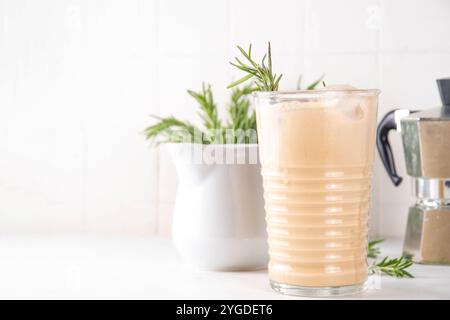 Glas aromatischer Rosmarin-Kaffee-Latte mit Eisduft, Schlagsahne oder Sahne, kaltes Kaffeegetränk mit Rosmarin-Zweig dekoriert Stockfoto