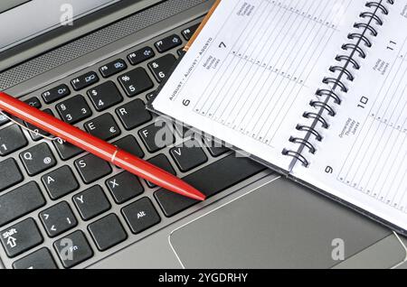 Roter Stift und Zeitplan liegen auf Laptop-Tastatur Stockfoto