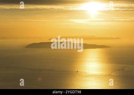 Kleine Insel und einsames Segelboot auf dem Meer während des dramatischen goldenen Sonnenuntergangs in der Nähe der Küste von Trapani, auf Sizilien, Italien, Europa Stockfoto