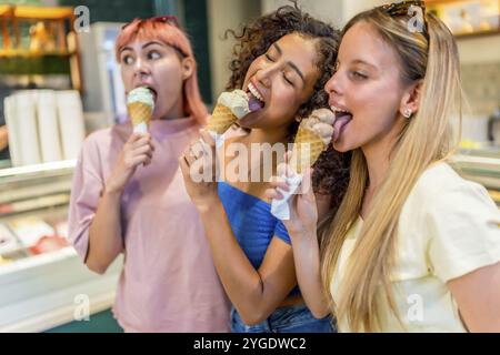 Drei verschiedene Frauen lecken ein leckeres Eis in einem Laden Stockfoto