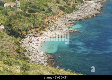 Schöner Strand mit Menschen, die an der Mittelmeerküste mit türkisfarbenem Wasser baden Stockfoto