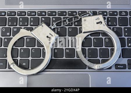 Handschellen, die auf einer Computertastatur liegen und Cyberkriminalität symbolisieren Stockfoto
