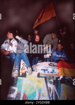 ARCHIVFOTO: Vor 35 Jahren, am 9. November 1989, fiel die Berliner Mauer. Am 9. November 1989 saßen und standen hauptsächlich junge Männer auf der Mauer. Ein Mann schlug mit einem Hammer auf die Mauer („Wall Woodpecker“). Querformat. ? Stockfoto