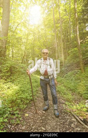 Älterer Wanderer am Anfang seiner Tour auf einem Weg im Wald im Morgenlicht Stockfoto