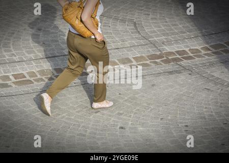Beine einer Frau, die eine gepflasterte Straße entlang geht Stockfoto