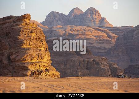 Jordanien, Wadi Rum, 2. November 2022: Kamelkarawane mit Schurken in der Wüste, Felsenberge bei Sonnenuntergang, Asien Stockfoto
