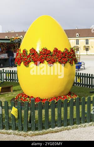 Wien, Österreich, 3. April 2015: Großes gelb dekoriertes Osterei auf dem Ostermarkt in der Nähe des Schlosses Schönbrunn in Wien und Menschen, die Ostern kaufen Stockfoto