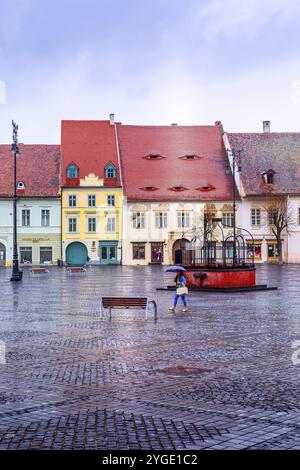 Sibiu, Rumänien, 27. März 2015: Häuser mit berühmten augenförmigen Fenstern auf den Dächern und Menschen auf dem Hauptplatz, Europa Stockfoto