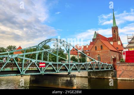 Breslau, Polen, 21. Juni 2019: Tumski-Brücke, die zum Bezirk Ostrow Tumski führt. Belfries der Kirche des Heiligen Kreuzes und der Kathedrale von St. Stockfoto