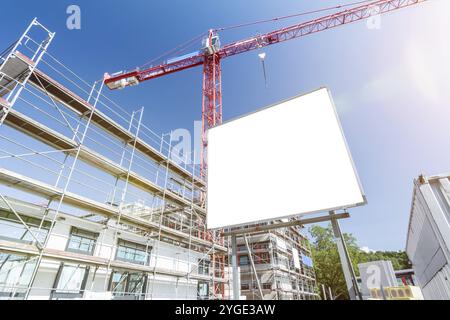 Weiße Plakatwand vor der Baustelle mit Gerüst und Kran Stockfoto