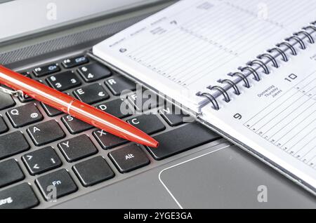 Roter Stift und Zeitplan liegen auf der Computertastatur Stockfoto
