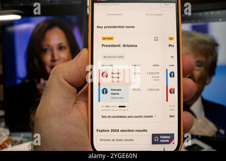 Paris, Frankreich - 6. November 2024: Ein Smartphone zeigt die Ergebnisse der US-Präsidentschaftswahlen 2024 für Arizona an und zeigt Donald Trump an der Spitze von Kamala Harris, mit Hintergrundbildern von Trump und Harris Stockfoto