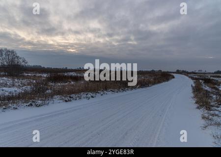 Winter landscape with sunset sky and empty snowy road. Stockfoto