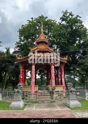 Traditioneller chinesischer Pavillon mit Statuen des Schutzlöwen in einer üppigen Parklandschaft Stockfoto