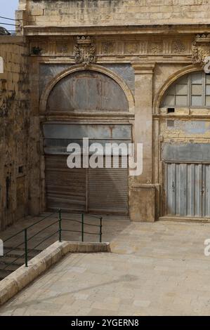 Valletta. Eisentür. Heruntergekommen. Wellblech. Haus. Erker. Kalkstein. bay-Fenster. Treppen. Treppe. Renovierungsbedürftig. Alt. Marode. alt. Kunstbügeltür. Stockfoto