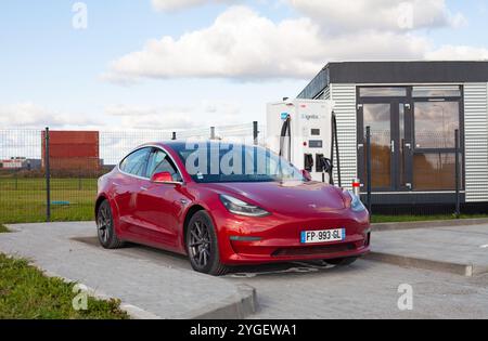 Rotes, vollelektrisches amerikanisches Auto Tesla Model 3 Dual Motor hat schnelles Laden auf dem Parkplatz mit superschneller Ladestation Stockfoto