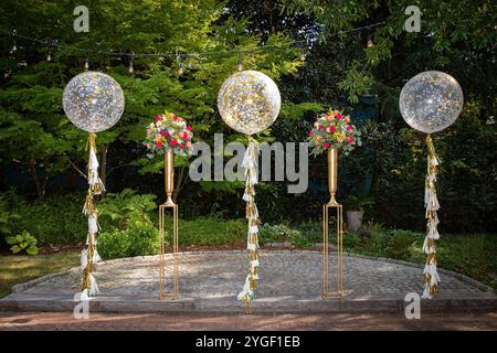 Elegante Hochzeitsdekoration im Freien mit Ballons und Blumenarrangements in einem malerischen Garten Stockfoto