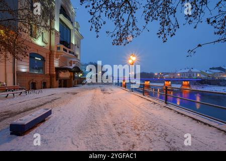 uschhorod, ukraine - 26. Dezember 2016: Urbane Landschaft mit Flussufer bei Sonnenaufgang. Winterferien Stadtbild. Das Licht der Innenstadt spiegelt sich im Wasser Stockfoto