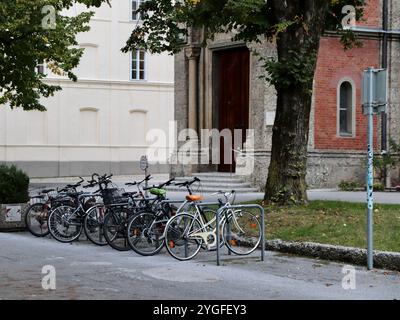 Salzburg, Österreich - 1. Oktober 2024: Fahrräder parken am historischen Gebäude im Europapark, umgeben von Bäumen und begehbarem Green Space. Hochwertiges Foto Stockfoto