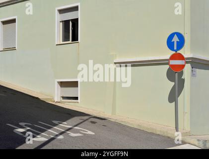 Verkehrsschilder und gemalte Worte halten an einer bergab Straße, Santa Teresa di Gallura, Sardinien, Italien Stockfoto