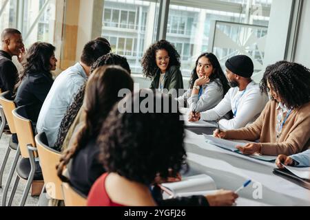 Vielfältige Gruppe in einem professionellen Umfeld, die an einem ansprechenden Workshop teilnimmt. Lächelnde Einzelpersonen genießen Teamarbeit und Training in einer hellen Konferenz Stockfoto