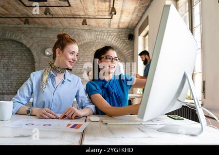 Unternehmerinnen, die in Coworking Space arbeiten, lächeln, Brainstorming als Team im Büro Stockfoto