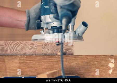 Handfräser in Aktion, die Kanten von Holzbrettern mit fachkundiger Handwerkskunst veredeln Stockfoto