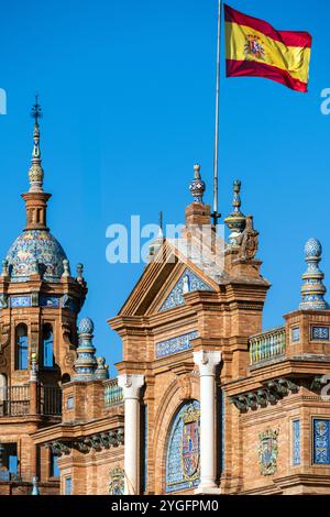 Nahaufnahme der komplexen architektonischen Details der Plaza de España in Sevilla, Spanien, mit traditionellen spanischen Designelementen und einer lebhaften Flagge Stockfoto