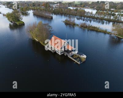 Kleines Freizeithaus auf der Loosdrechtse Plassen, Drohnenvideo. Winziges Haus umgeben von Wasser in den Niederlanden. Herbstfarben. Stockfoto