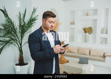 Ein junger, lächelnder Mann in einer Jacke spricht am Telefon. Emotionen des Lachens, wenn man am Telefon spricht. Ein erfolgreicher Mann arbeitet aus der Ferne am Telefon. Stockfoto
