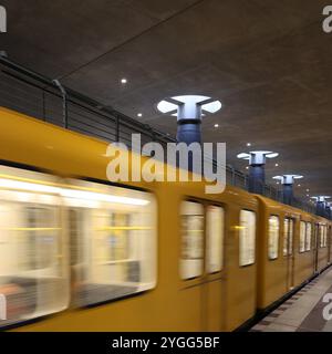 U-Bahn. Berlin. Bundestag. Durchfahrender Zug. Vorbeifahrender Zug. Gelber Zug. Kamera. Plattform. Schnell. Säulen. Beton. Tageslicht. Moderne Architektur. Stockfoto