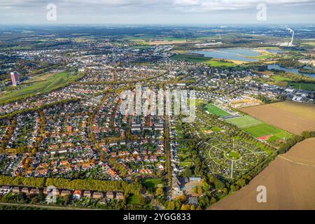 Luftbild, Wohngebiet an der Ebertstraße und kreisrunder KGV Kleingartenverein Sonnenblume, rechts Baustelle und Neubau halbrundes Wohngebiet an der Franzstraße am Volkspark, Sportplatz Fußballstadion 1. FC Lintfort 1914/26 e.V., links Zechenpark Friedrich Heinrich LAGA Park, ehemaliges RAG Bergwerk West mit Zechenturm und Förderturm, hinten Kiesbaggersee mit Abfallentsorgungszentrum Asdonkshof, Rossenray, Kamp-Lintfort, Ruhrgebiet, Nordrhein-Westfalen, Deutschland ACHTUNGxMINDESTHONORARx60xEURO *** Luftansicht, Wohngebiet an der Ebertstraße und kreisförmiger Kleingartenverband Sonnenblu Stockfoto