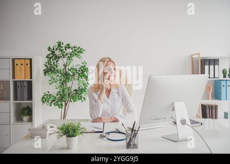Reife Ärztin in Klinikpraxis, die an Aufgaben der Computermedizin arbeitet Patientenberatung in einem professionellen Umfeld. Stockfoto
