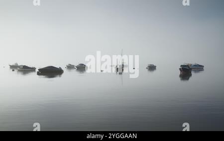 Motorboote, Segelboote vor Anker im Hafen von Christchurch an Einem ruhigen Tag ohne Wind in Sea Mist, Fog, Christchurch, Großbritannien Stockfoto